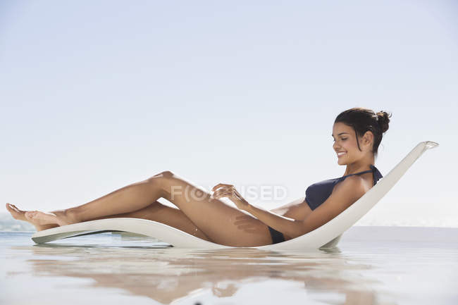 Улыбающаяся молодая женщина загорает на пляже — стоковое фото