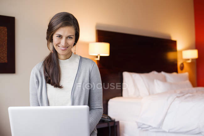 Porträt einer lächelnden Frau mit Laptop im Hotelzimmer — Stockfoto