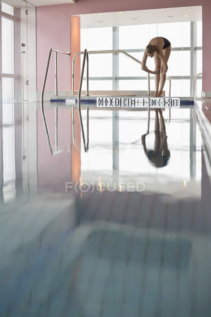 Slim woman in swimwear diving into indoor swimming pool — Stock Photo