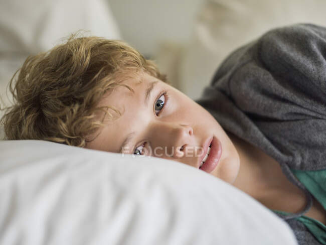 Мальчик лежал на кровати — стоковое фото
