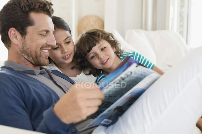 Homem lendo uma revista com seus filhos — Fotografia de Stock