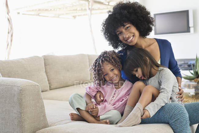 Mujer sonriente sentada con sus dos hijas - foto de stock