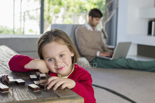 Портрет улыбающейся девушки с отцом, использующей ноутбук на заднем плане — стоковое фото