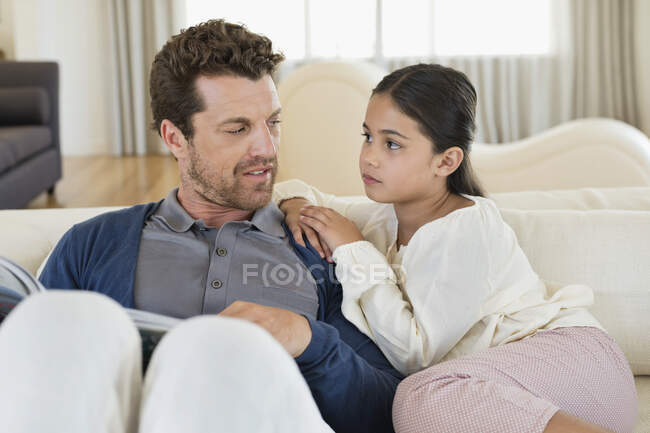 Чоловік сидить зі своєю дочкою і читає журнал — стокове фото