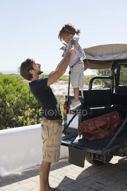 Мужчина играет со своей дочерью возле внедорожника — стоковое фото