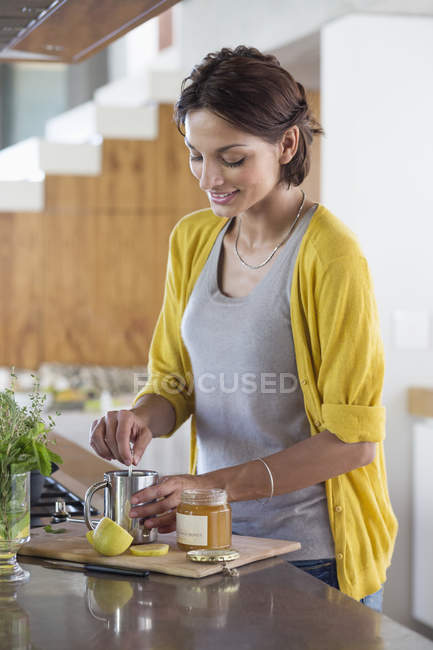 Donna sorridente che prepara tisane in cucina moderna — Foto stock