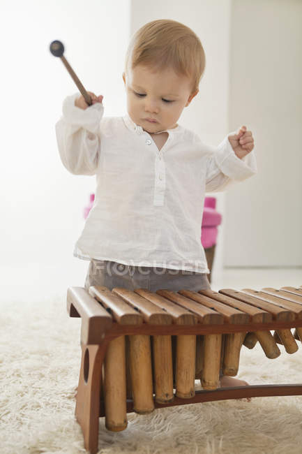 Baby boy playing xylophone on white furry carpet — Stock Photo