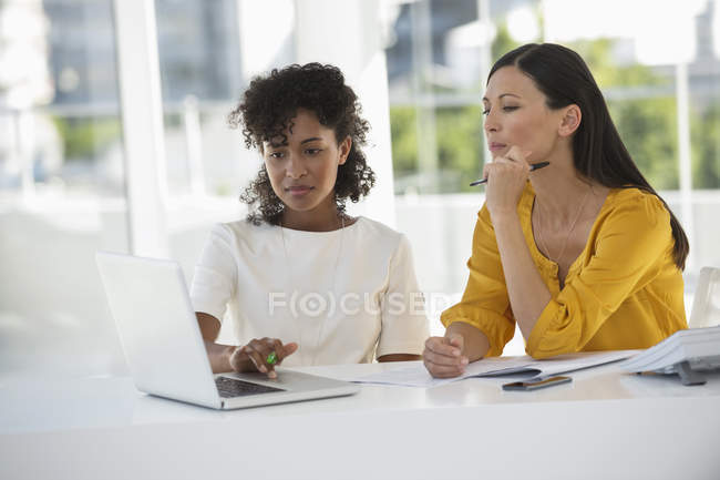 Two female coworkers working on laptop in office — Stock Photo