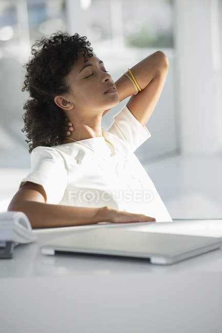 Donna che si rilassa sulla sedia alla scrivania con computer portatile in ufficio — Foto stock