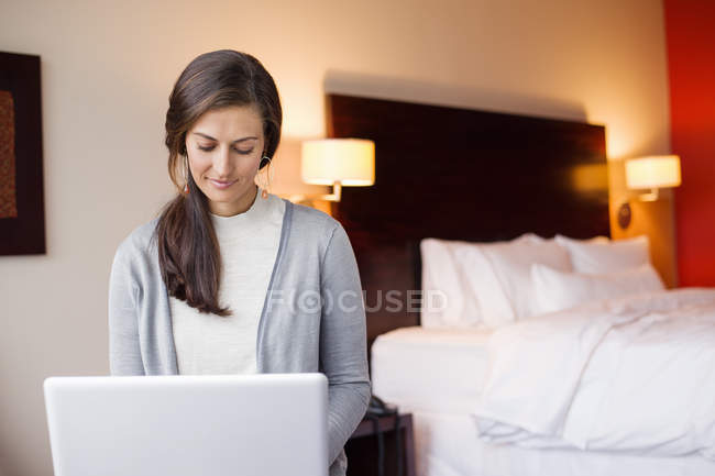 Портрет усміхненої жінки з ноутбуком, що сидить у готельному номері — стокове фото