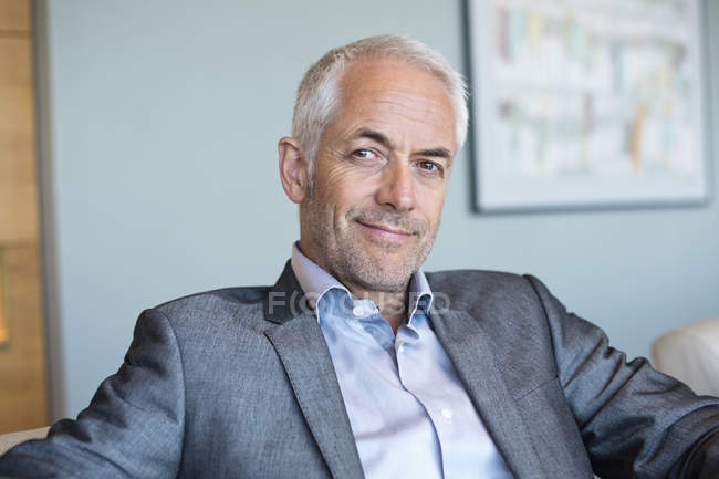 Retrato de sorrir confiante maduro empresário sentado e pensando — Fotografia de Stock