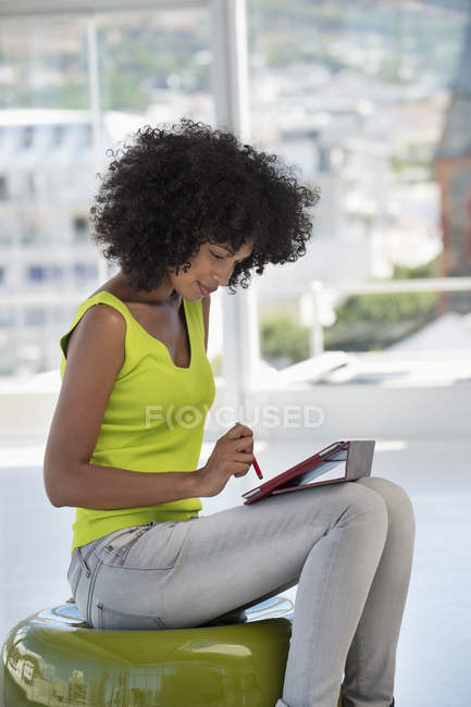 Smiling woman in bright yellow top using digital tablet — Stock Photo