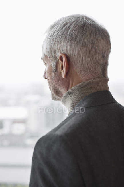 Homem maduro pensativo olhando através da janela — Fotografia de Stock