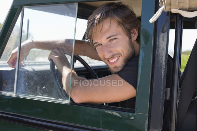 Young man sitting in vehicle and looking out of window — Stock Photo