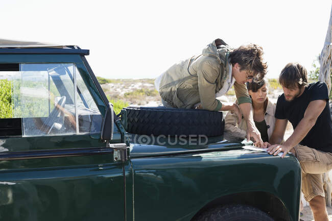 Friends looking at map beside a SUV — Stock Photo