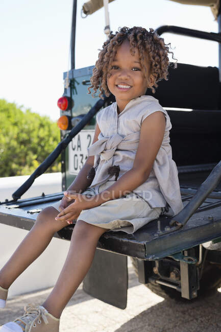 Retrato de uma menina sentada em um SUV e sorrindo — Fotografia de Stock
