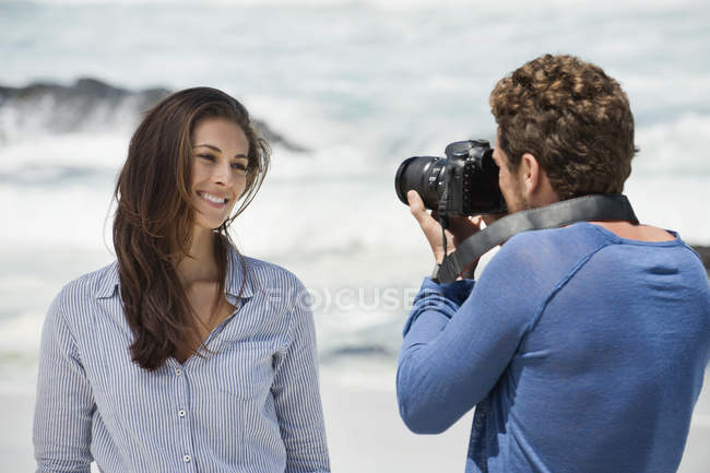 Homem tirando foto da esposa com câmera na praia — Fotografia de Stock