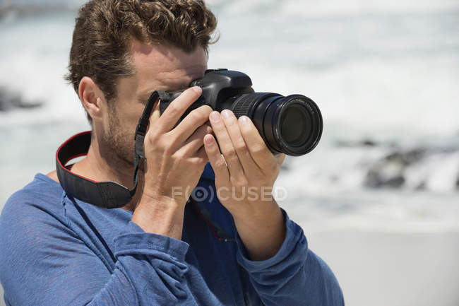 Closeup of man with camera photographing on beach — Stock Photo