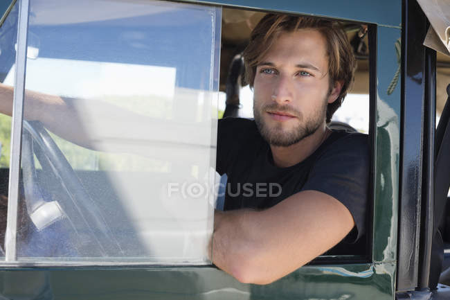 Young man sitting in vehicle and looking out of window — Stock Photo
