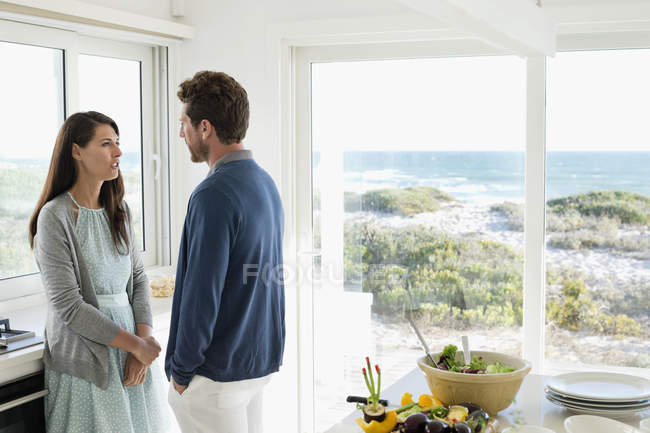 Coppia parlando e guardando l'un l'altro in cucina di casa costiera — Foto stock