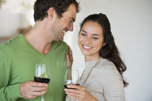 Casal segurando copos de vinho e sorrindo — Fotografia de Stock