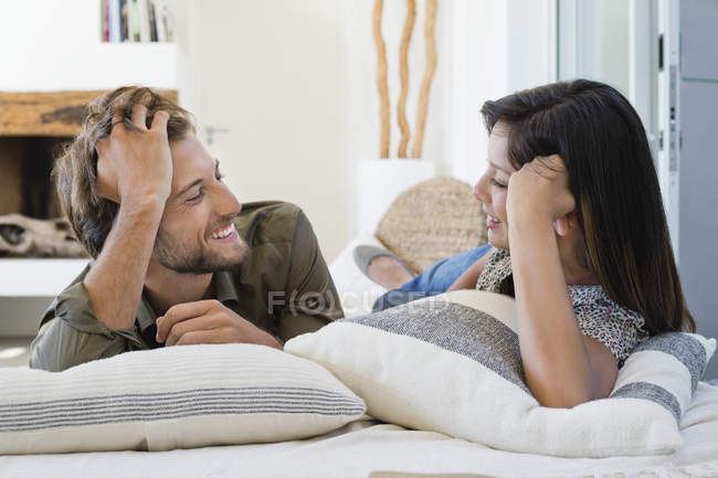 Smiling couple lying on bed and talking — Stock Photo
