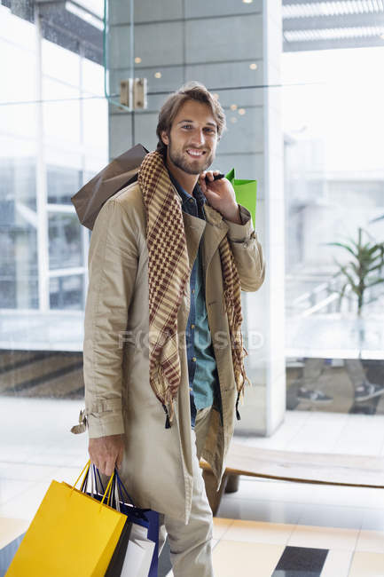 Retrato de un hombre joven y elegante que lleva bolsas de compras - foto de stock