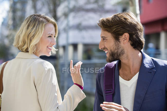 Улыбающиеся мужчина и женщина смотрят друг на друга на улице — стоковое фото