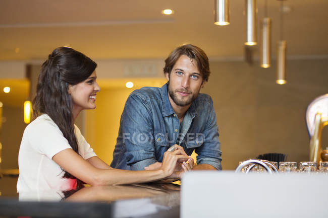 Smiling young couple sitting at a bar counter — Stock Photo