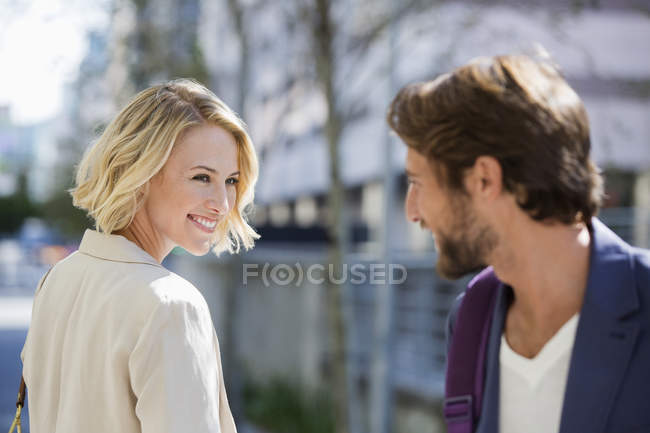 Улыбающиеся мужчина и женщина смотрят друг на друга на улице — стоковое фото