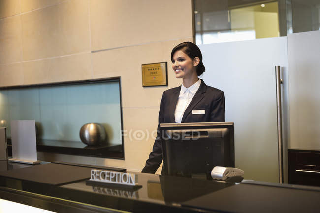 Female receptionist standing at hotel reception counter and smiling — Stock Photo