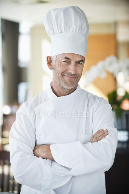 Retrato de confiado y sonriente chef masculino con los brazos cruzados en el restaurante - foto de stock