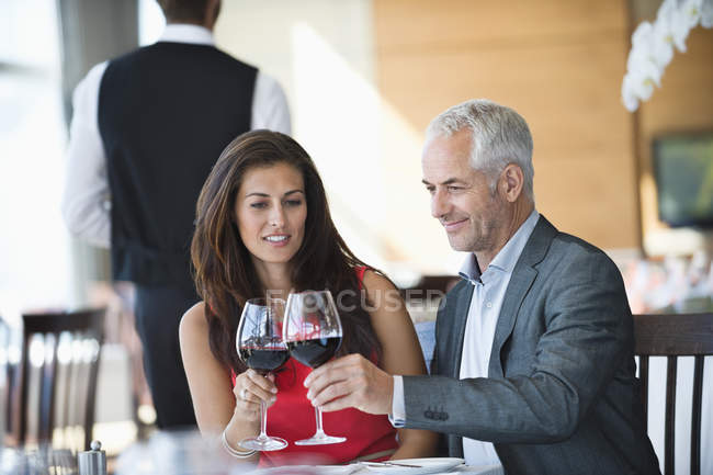 Casal desfrutando de vinho tinto no restaurante — Fotografia de Stock