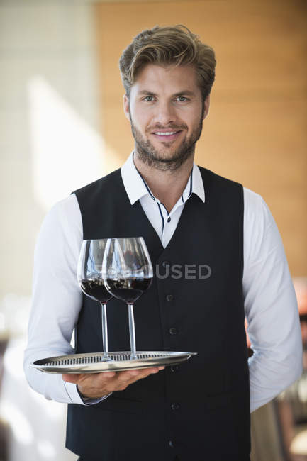 Portrait of waiter holding tray of wine glasses in a restaurant — Stock Photo