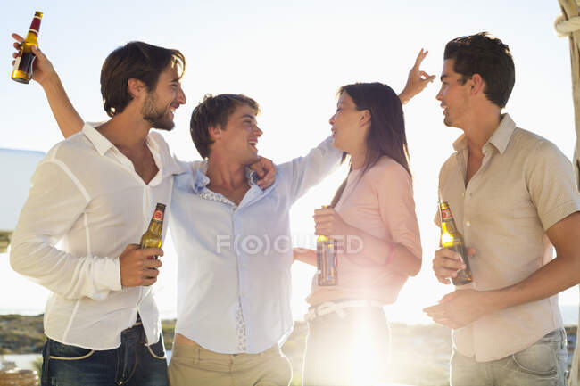 Four friends enjoying beer in party — Stock Photo