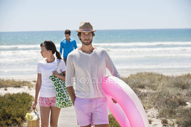 Amigos caminando en un paseo marítimo en la playa - foto de stock