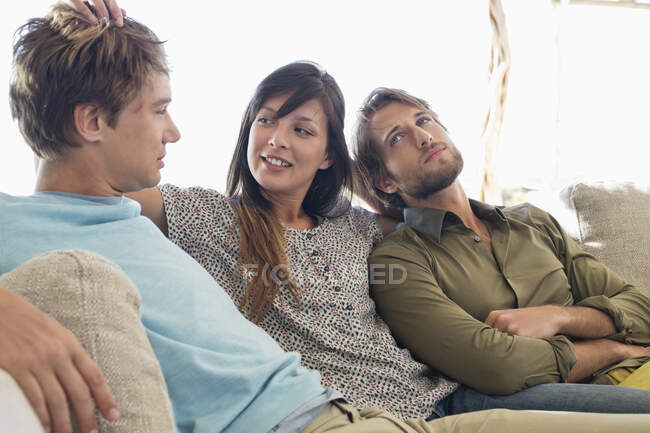 Tres amigos sentados juntos en un sofá - foto de stock