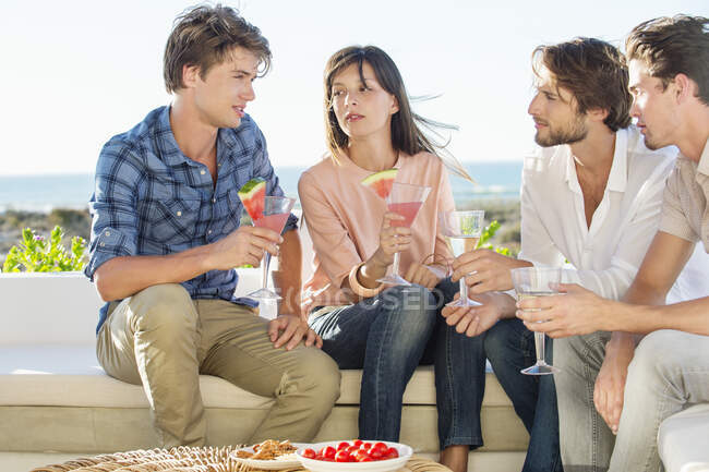 Grupo de amigos disfrutando de bebidas al aire libre de vacaciones - foto de stock