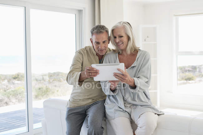 Sorrindo casal sênior usando tablet digital em casa — Fotografia de Stock