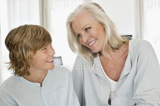 Mujer y su nieto sonriéndose el uno al otro - foto de stock