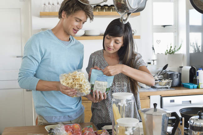 Smiling young couple cooking in kitchen — Stock Photo