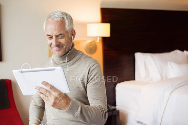 Мужчина смотрит фильм на цифровом планшете в номере отеля — стоковое фото