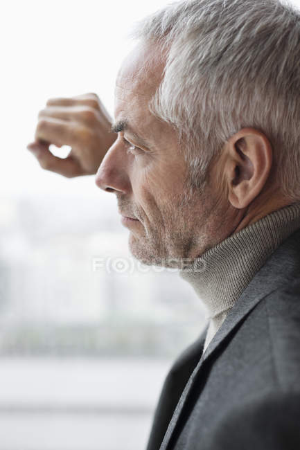 Confident pensive mature man looking through window — Stock Photo
