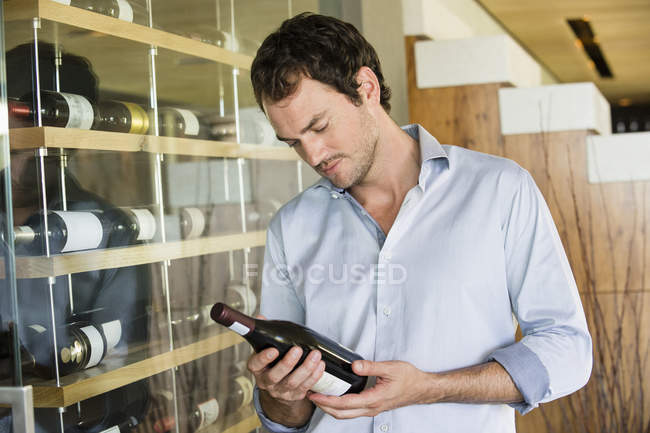 Homme élégant regardant bouteille de vin — Photo de stock