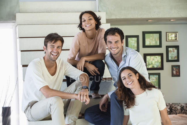 Portrait of smiling friends sitting on steps — Stock Photo