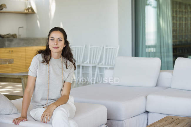 Портрет усміхненої жінки, що сидить на дивані в сучасній квартирі — стокове фото