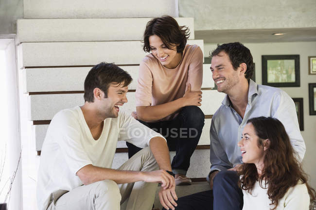 Усміхнені друзі сидять на сходах і розмовляють — стокове фото