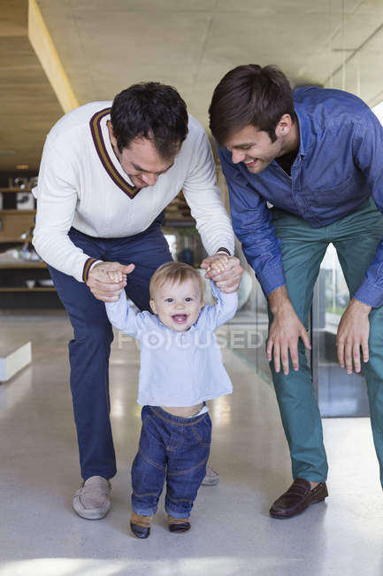 Happy lgbt parents helping son to walk at home — Stock Photo