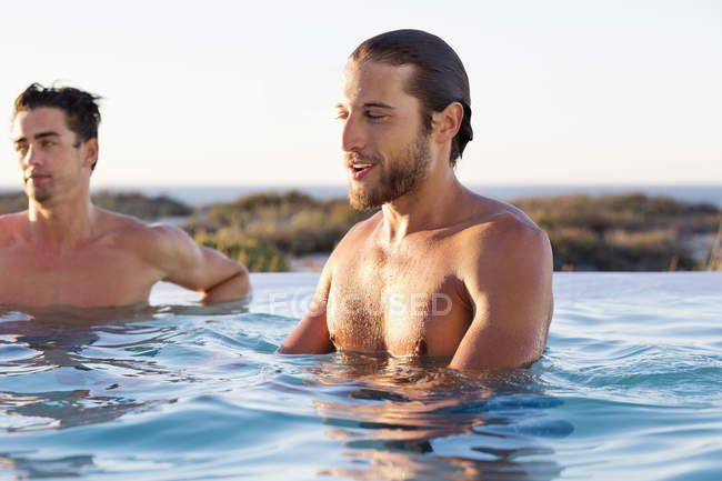 Male friends enjoying in swimming pool in nature — Stock Photo