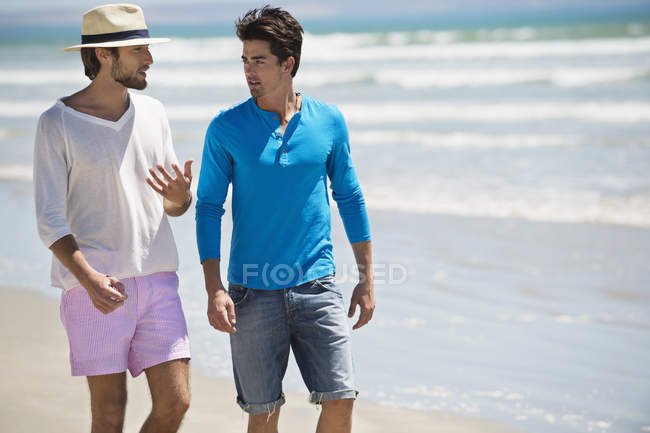 Розслаблених чоловіків, що ходять на пляжі з хвилястим морем — стокове фото